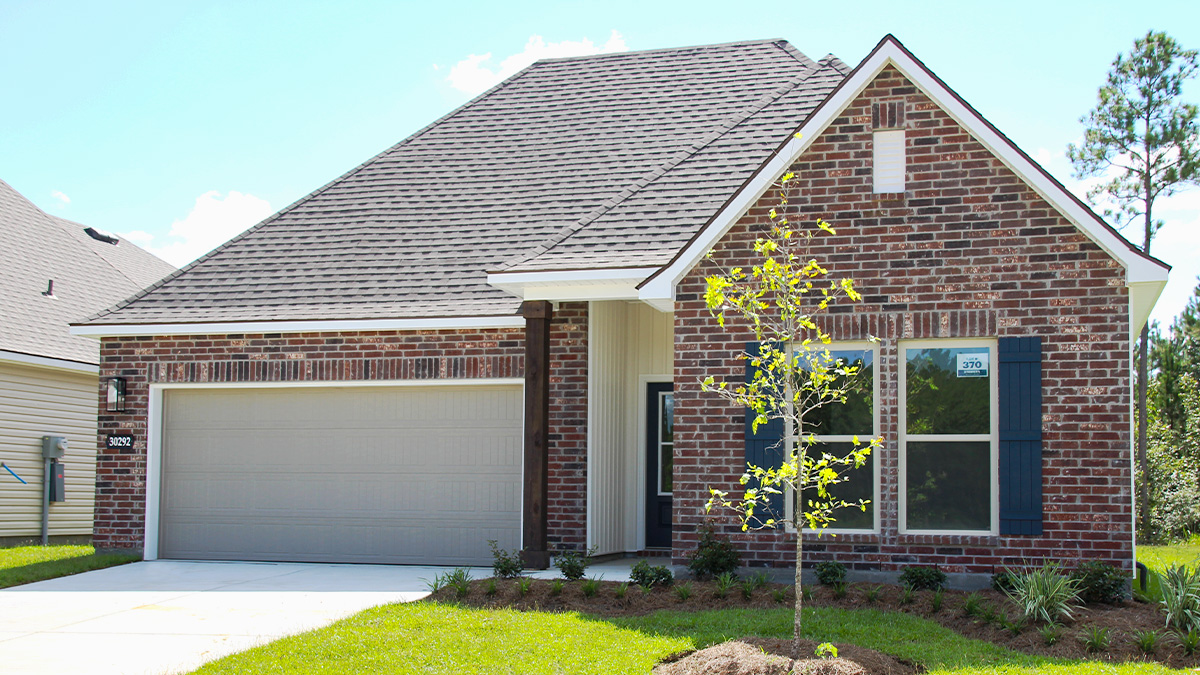Single-story home with red brick. Black glass front door with dark grey shutters and white trim.