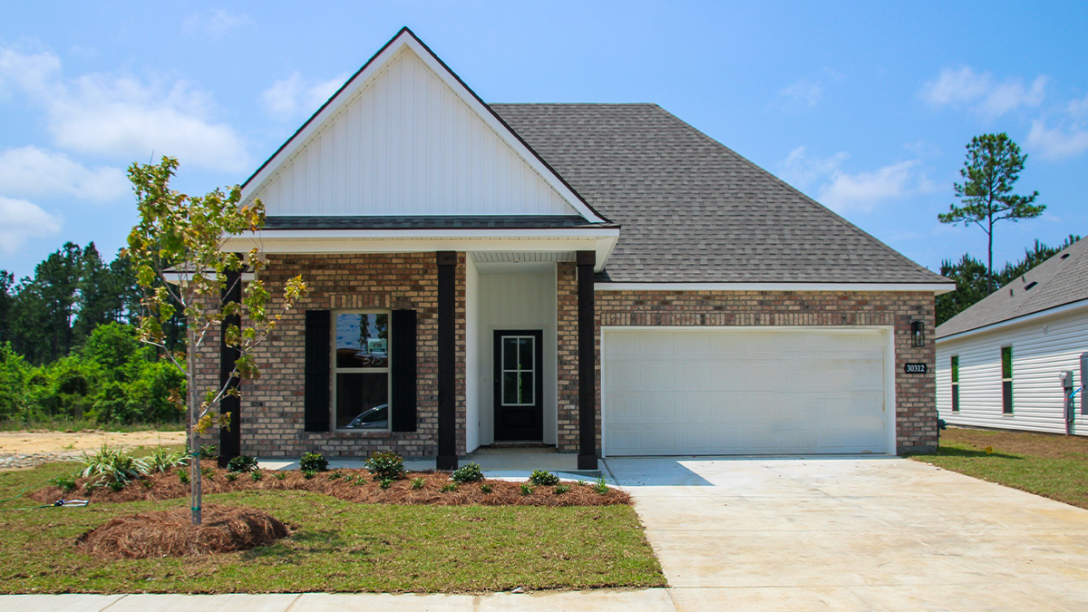 single-story home with tan brick and white vinyl siding with bleck front door and shutters with porch and two-car garage