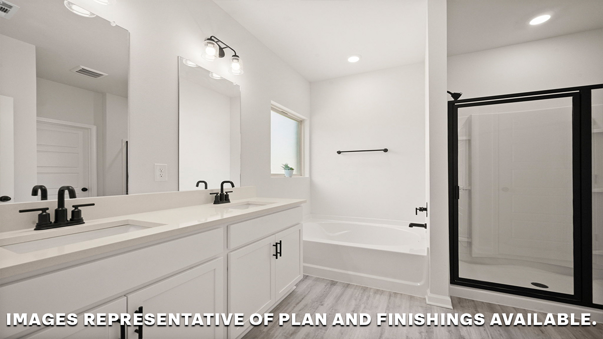 primary bathroom with dual vanities, mirror and separate shower and tub