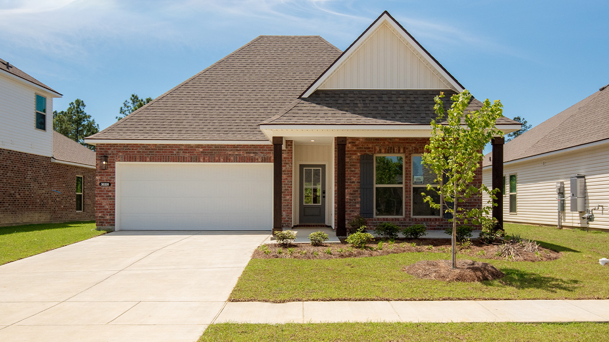 single-story home with red brick and tan vinyl siding with black front door and shutters with porch and two-car garage