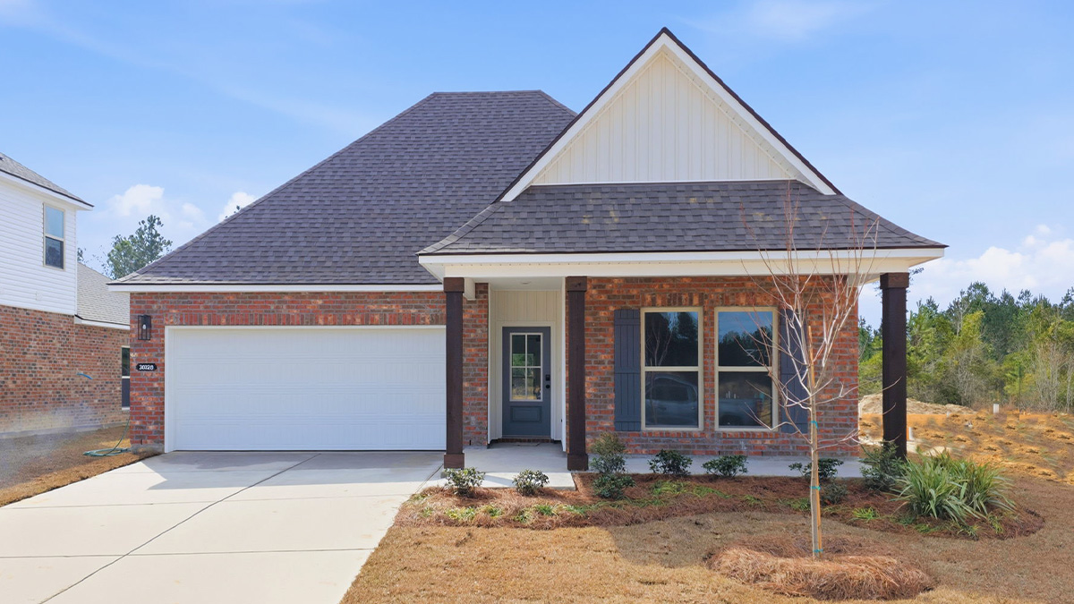 single-story home with red brick and tan vinyl siding with black front door and shutters with porch and two-car garage