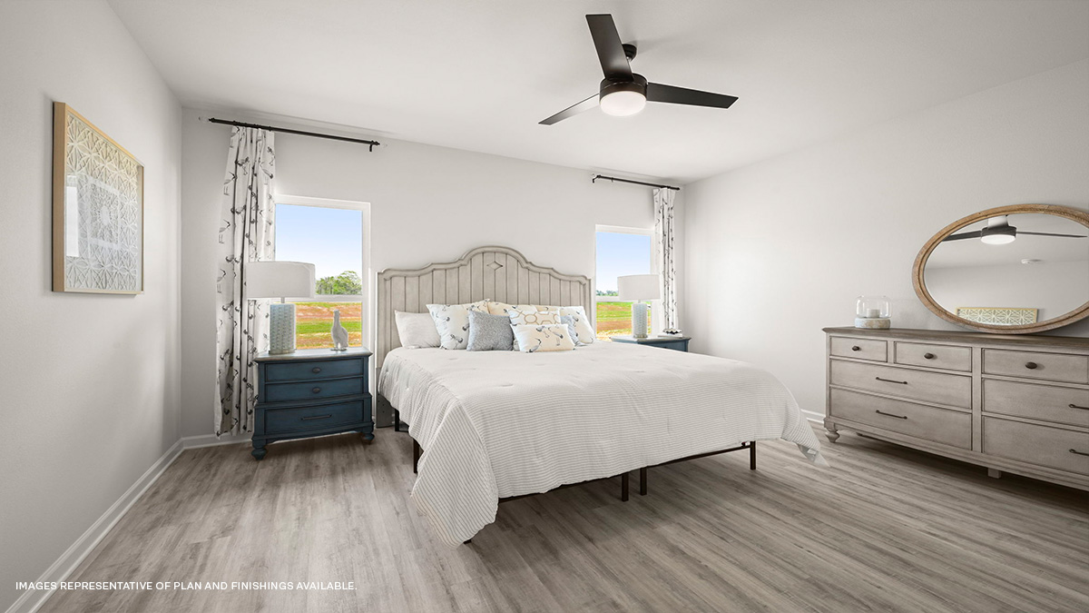 Large primary bedroom with dual windows overlooking the backyard