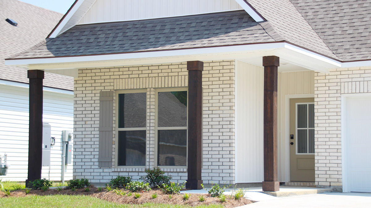 Single-story home with white brick. Cream glass front door with cream shutters and white trim.