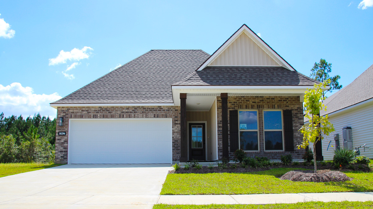 single-story home with tan brown brick with tan vinyl siding with bleck front door and shutters with two-car garage