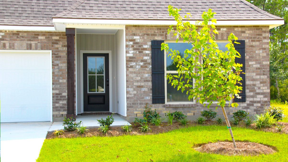 Single-story home with brown brick. Black glass front door with black shutters and white two car garage.