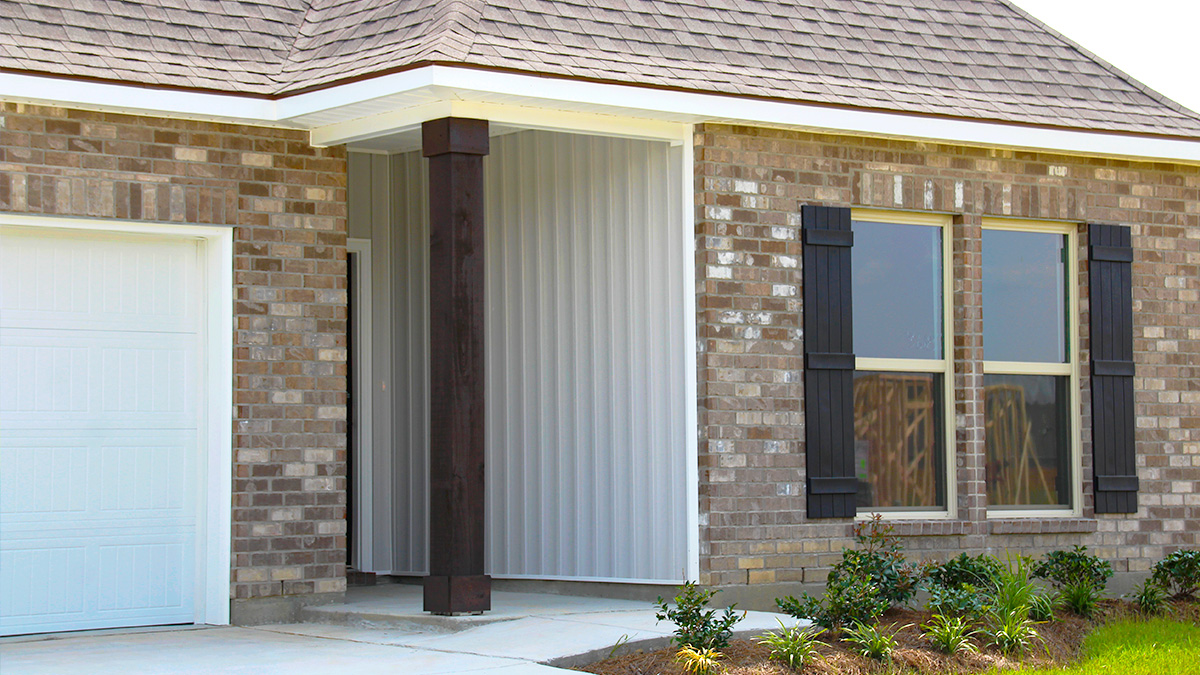 Single-story home with brown brick. Black glass front door with black shutters and white two car garage.