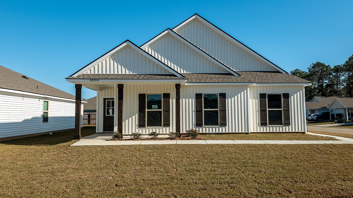 Single-story home with light tan vinyl siding and brown front door and shutters with porch