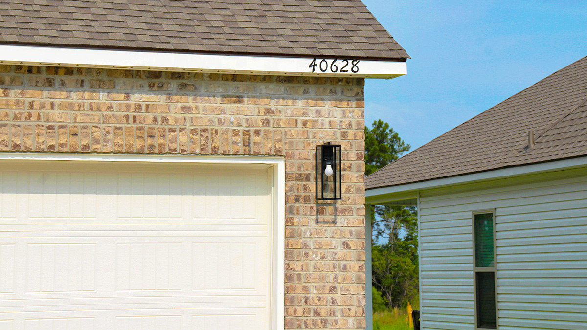 Two-story home with tan hardie vinyl and tan brick. Blue glass front door with brown shutters and white two car garage.