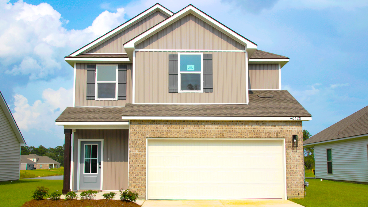 Two-story home with tan hardie vinyl and tan brick. Blue glass front door with brown shutters and white two car garage.