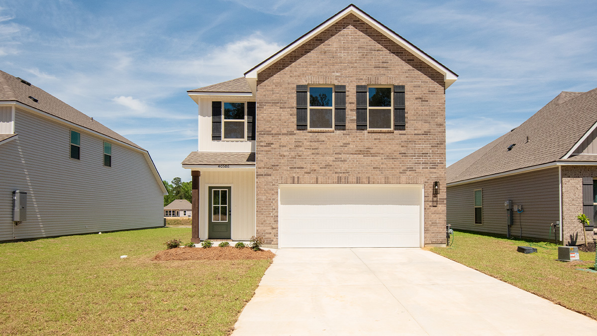 double-story home with brown brick and tan vinyl siding with green front door and black shutters with two-car garage