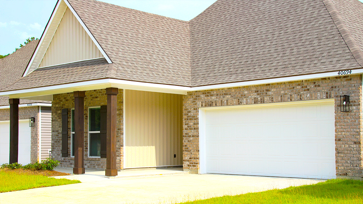 Single-story home with brown brick. Black glass front door with black shutters and white trim.