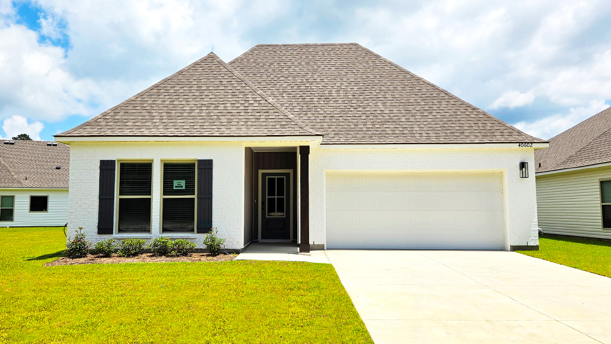 Single-story home with white brick. Black glass front door with black shutters and 2 car white garage.