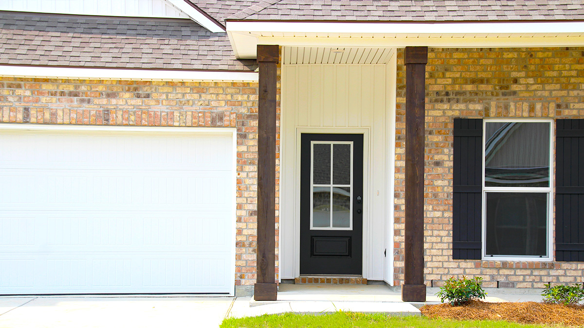Single-story home with brown brick and white hardie vinyl. Black glass front door with black shutters and white two car garage.