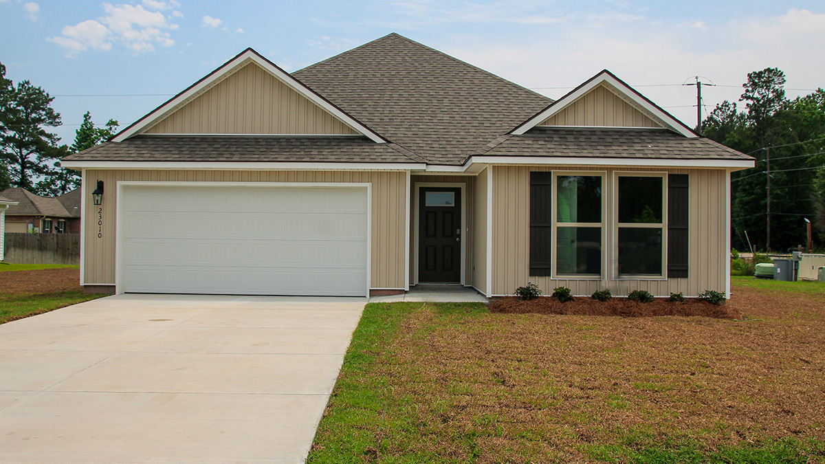 single-story home tan vinyl siding with brown front door and shutters with two-car garage