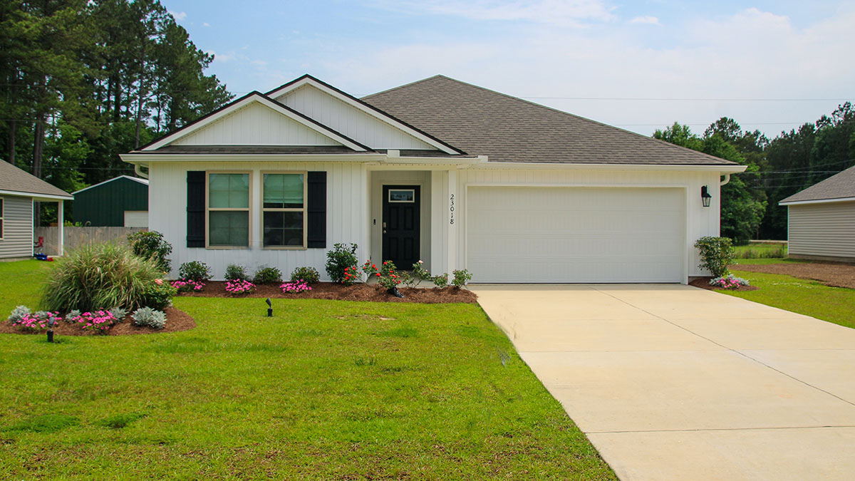 single-story home with white vinyl siding and black front door and shutters with two-car garage
