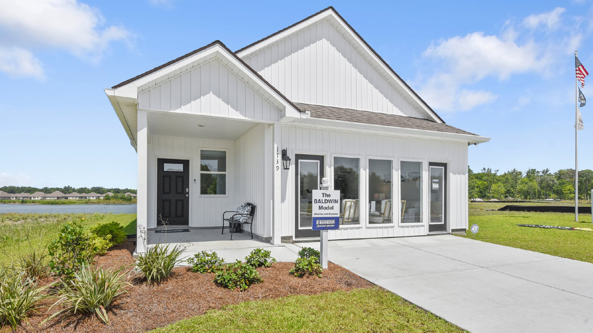 single-story home with white vinyl siding and black front door and porch with two-car garage