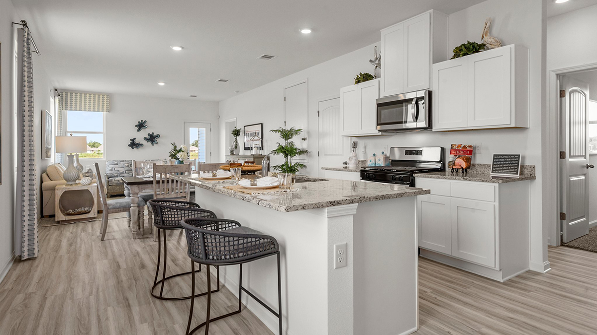 white kitchen island cabinets with stainless steel appliances and stools and access to dining room