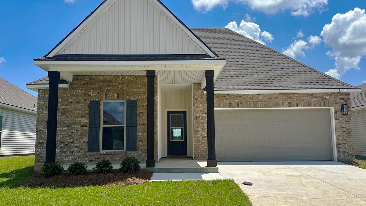 Single-story home with brown brick. Black glass front door with black shutters and white trim.