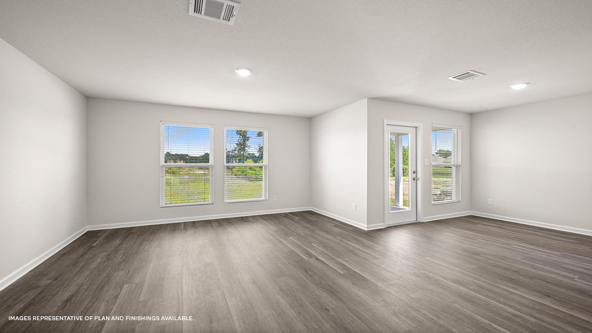 Open-concept living room with dual windows facing rear of home and dining space