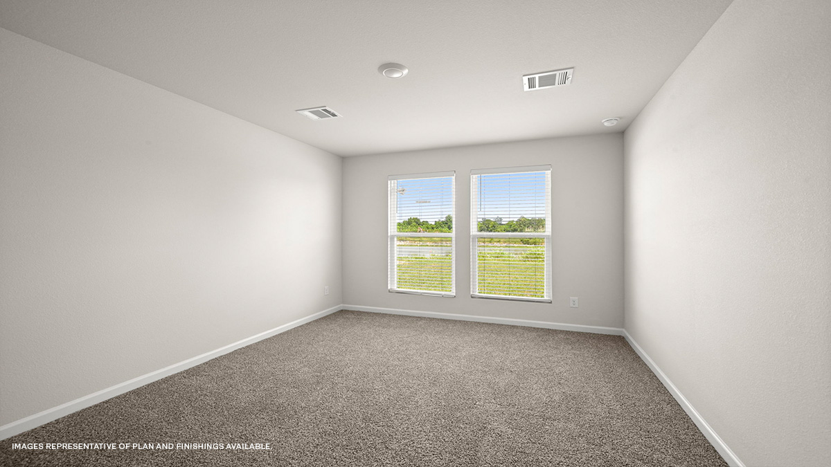 Large primary bedroom with dual windows overlooking the backyard