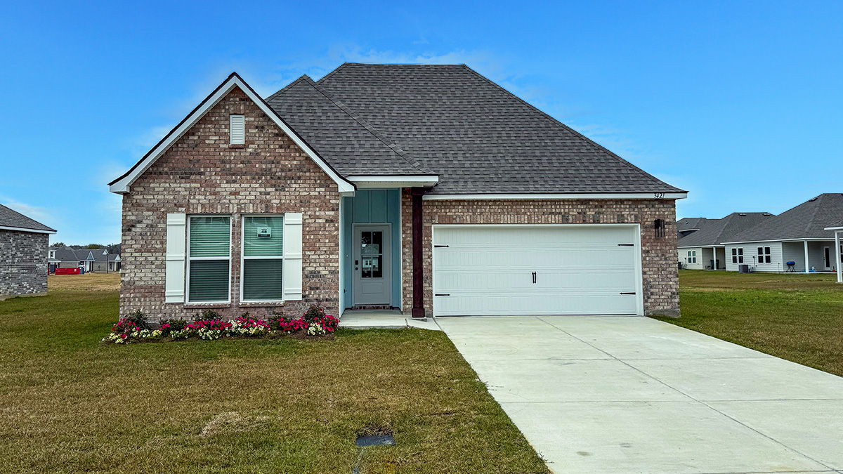 single-story home with tan brick and light hardie siding with white front door and shutters with two-car garage