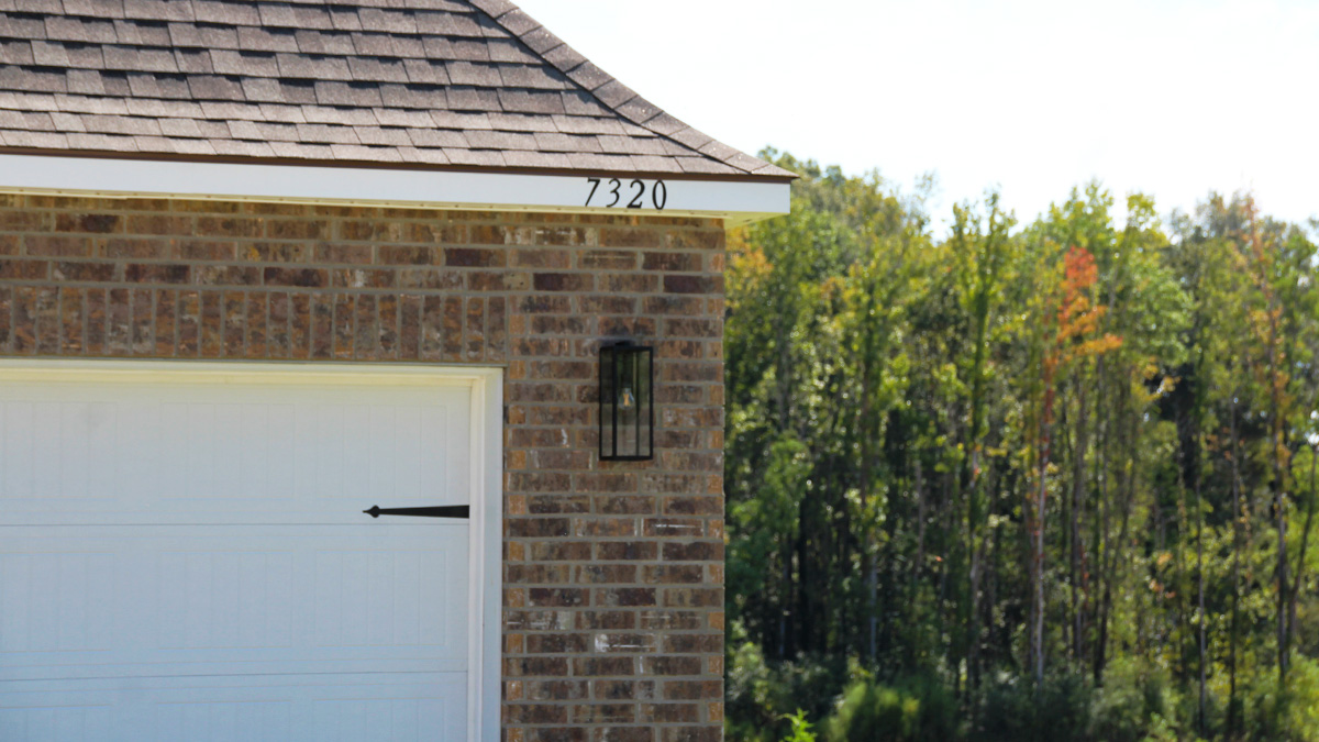 Single-story home with dark grey brick. Dark brown glass front door with black shutters and white trim.