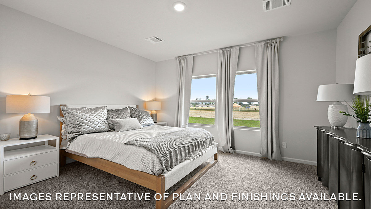Large primary bedroom with dual windows overlooking the backyard