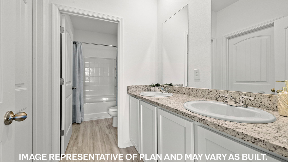 primary bathroom with dual vanities and opening to shower tub combo and toilet space