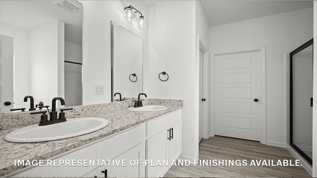 primary bathroom with dual vanities and opening to walk in closet