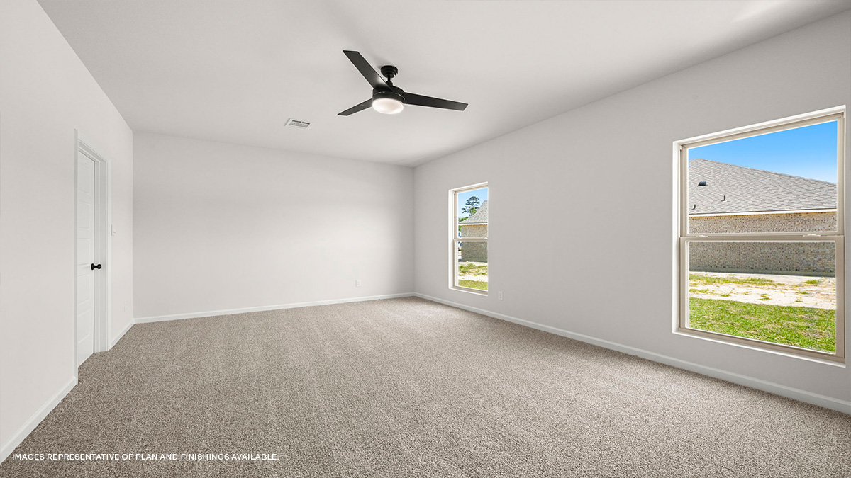 primary bedroom with fan and dual windows with access to bath