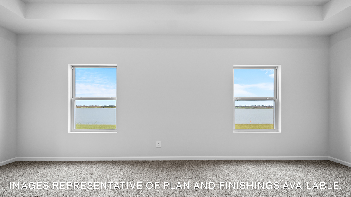 Large primary bedroom with dual windows overlooking the backyard