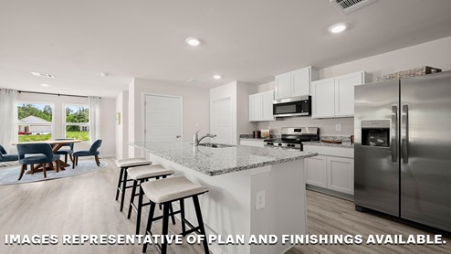 White kitchen island and open dining room with access to patio