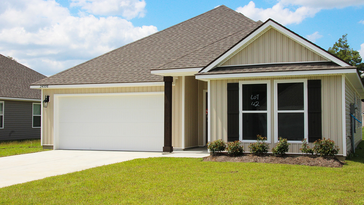 Single-story home with tan vinyl. Black glass front door with black shutters and white trim.
