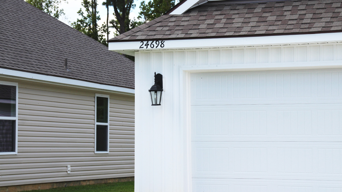 Single-story home with white brick. Black glass front door with black shutters and white trim.