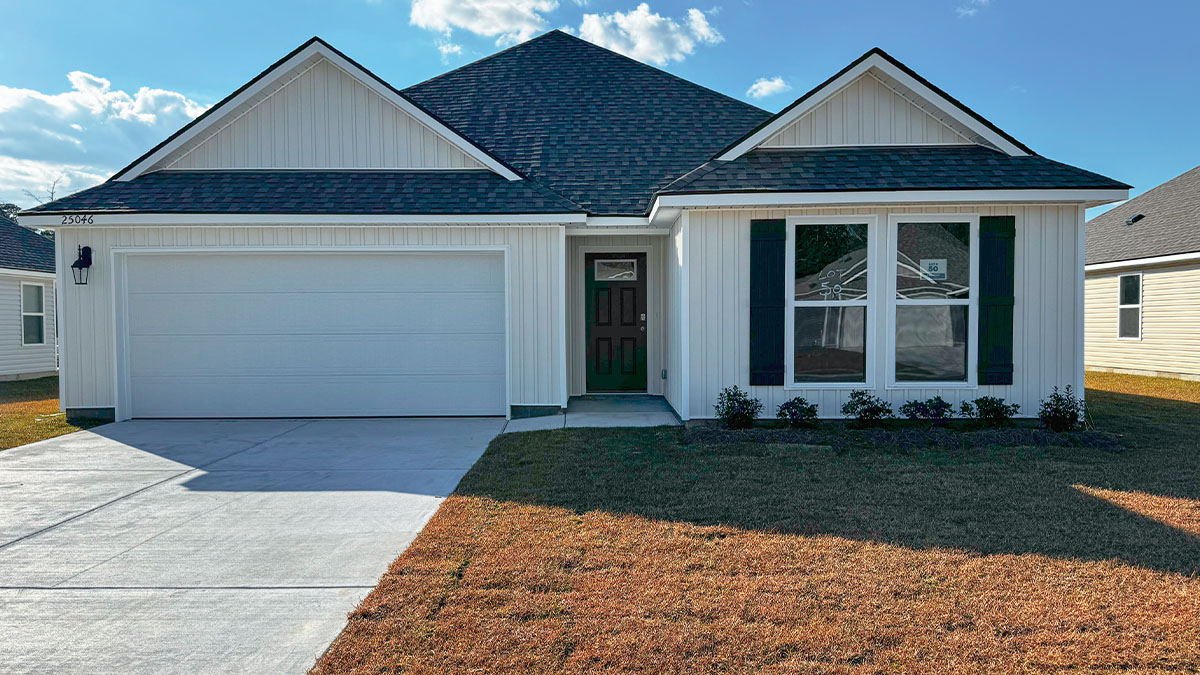 single-story home with tan vinyl siding with brown front door and black shutters with two-car garage