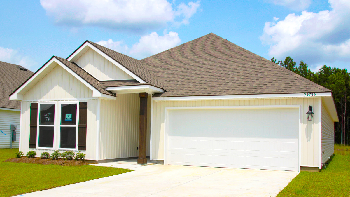 Single-story home with cream Vinyl with brown shutters and black door. White two car garage.