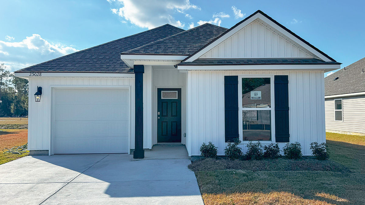 single-story home with white vinyl siding and black front door and shutters with two-car garage