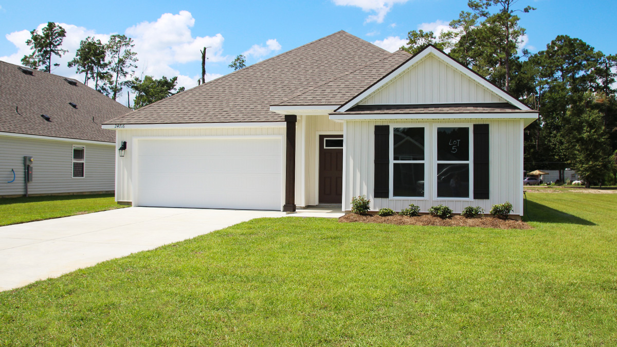 Single-story home with white brick. Black glass front door with black shutters and white trim.