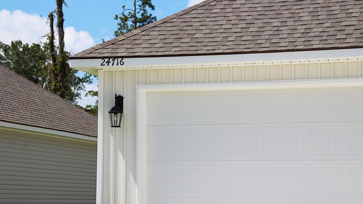 Single-story home with white brick. Black glass front door with black shutters and white trim.