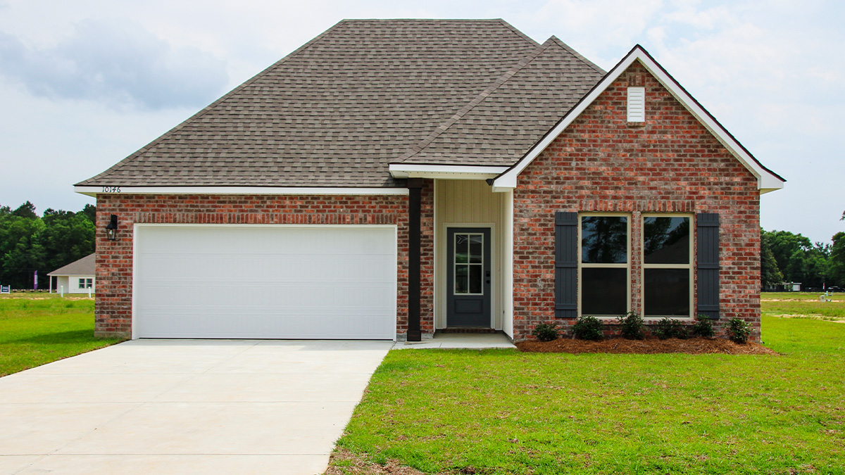 single-story home with red brick and black front door and shutters with two-car garage