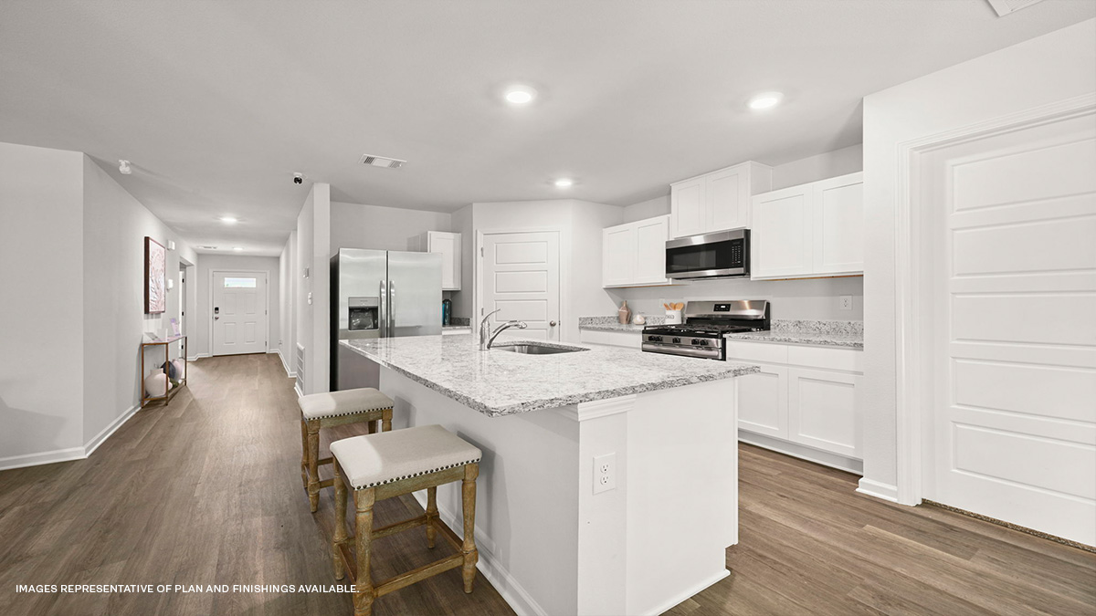 white kitchen cabinets and island with stainless steel appliances and foyer access