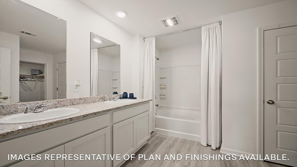 primary bathroom with dual vanities, mirror and shower tub combo