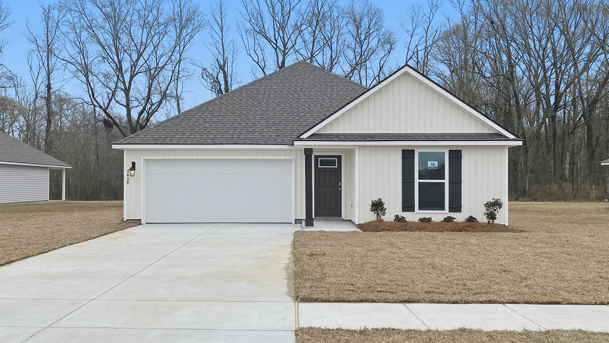 single-story home with tan vinyl siding with black front door and shutters with two-car garage