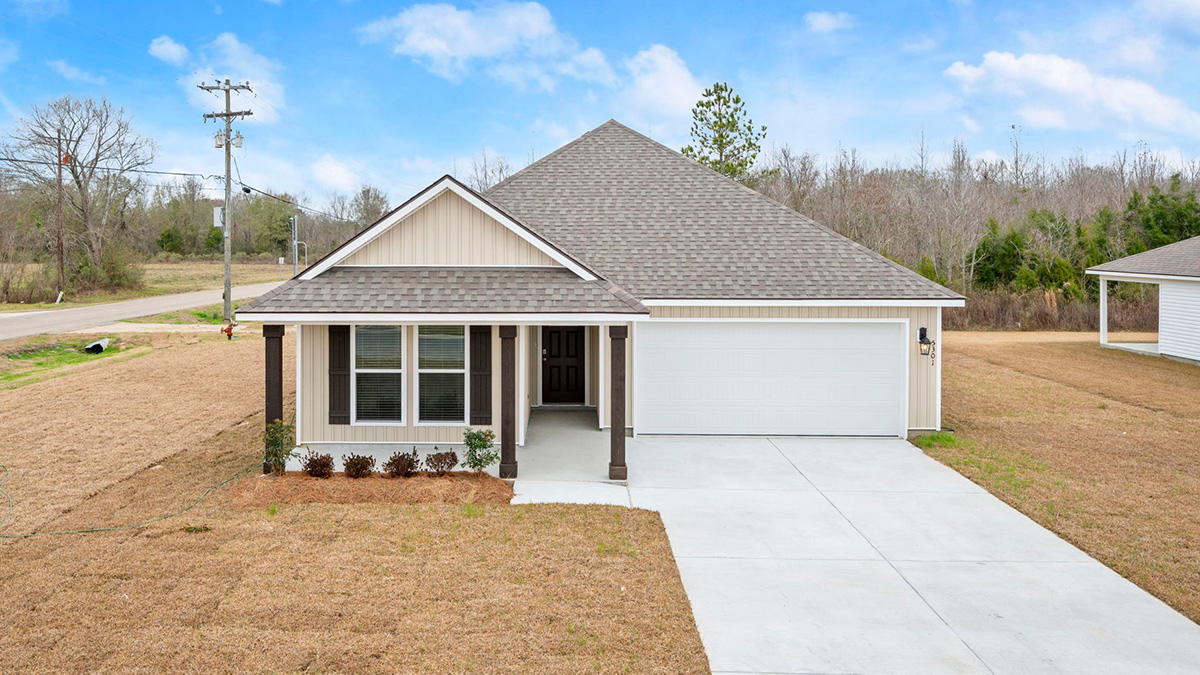 single-story home with tan vinyl siding and brown front door and shutters with two-car garage and porch