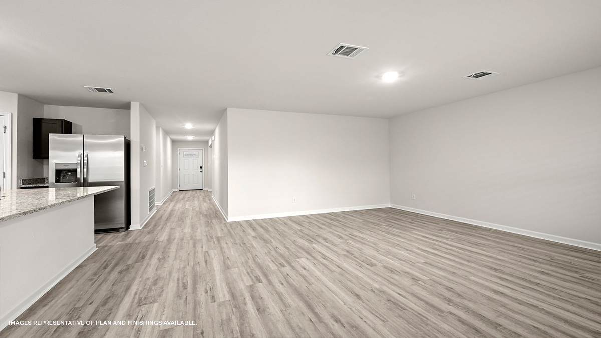 Rear view of open-concept living space with kitchen island and stainless steel appliances with foyer