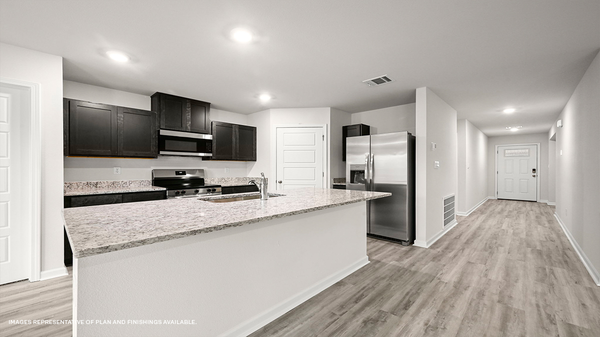 Dark grey kitchen cabinets and island with stainless steel appliances and foyer access