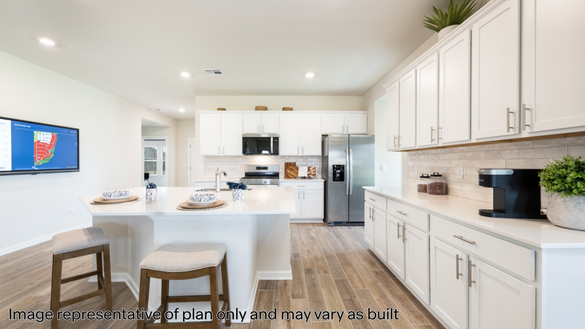 Kitchen with white cabinetry, a kitchen bar, appliances with stainless steel finishes, a center island with sink, and wood finish floors