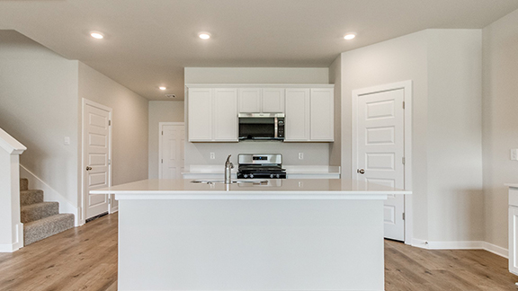 Kitchen with white cabinets, an island with sink, stainless steel appliances, light wood finished floors, and recessed lighting