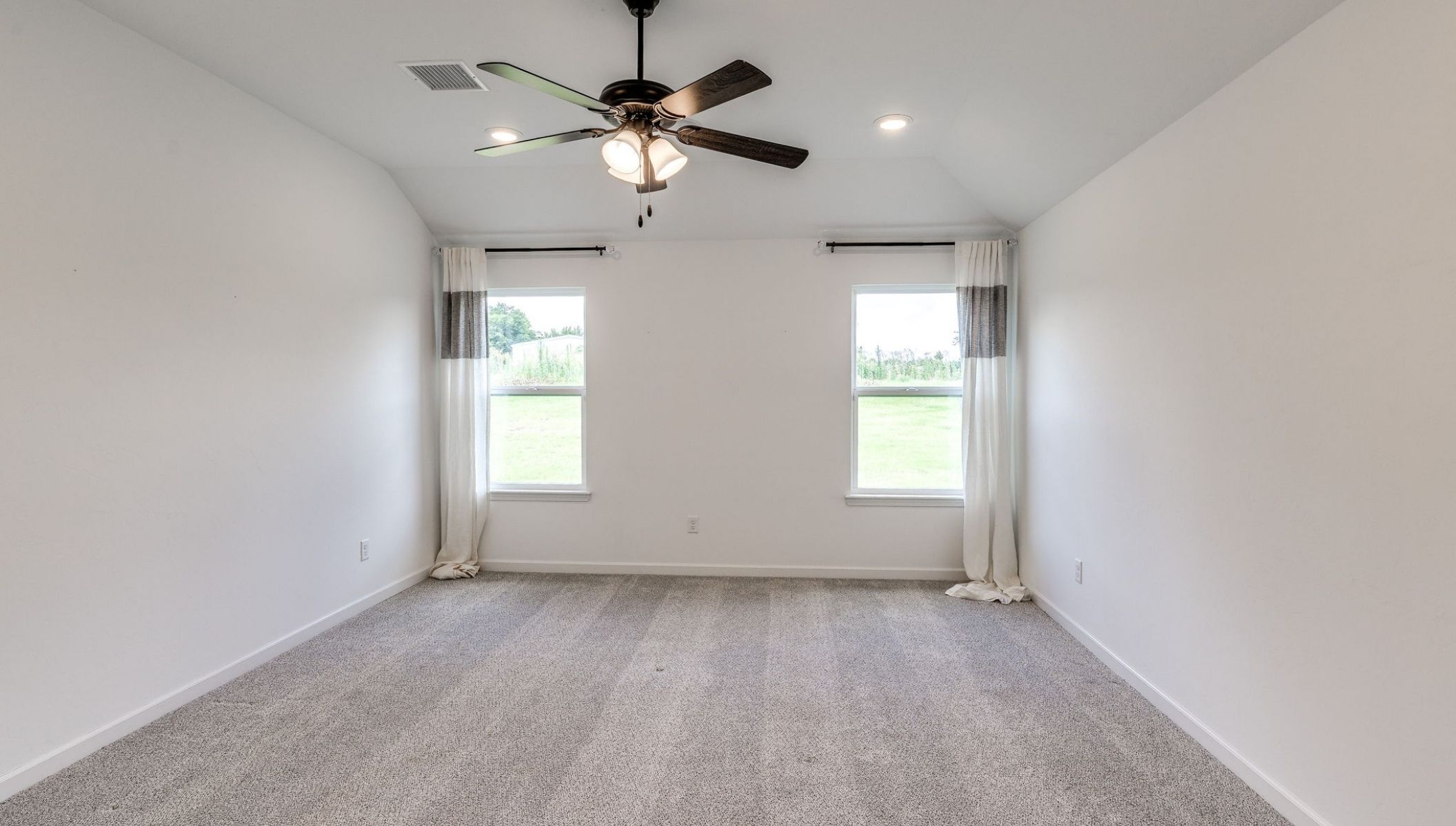 primary bedroom with fan and two windows