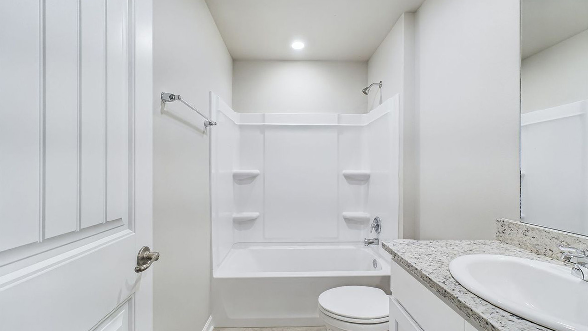 The single story Catahoula home plan bathroom has modern fixtures, closet space and granite countertops.